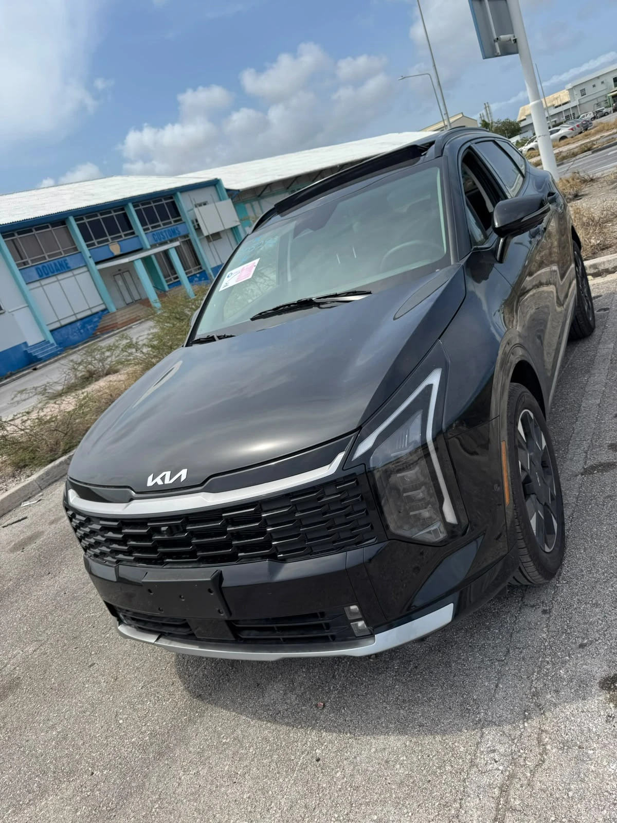 Black Kia Sportage parked in front of the Douane customs building in Curaçao